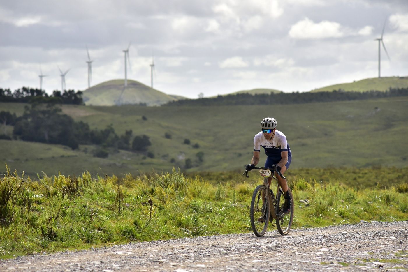 Ciclista del Scott Gravel solo en un camino de ripio, con los molinos de fondo